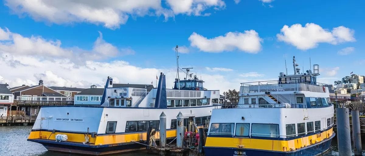 Passenger ferries docked at a harbor pier under a blue sky