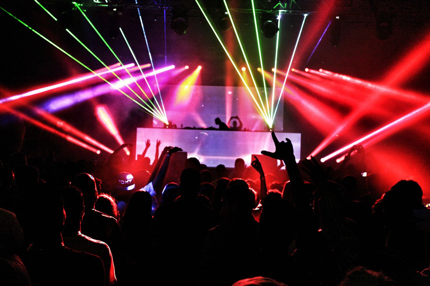 Crowd dancing under colored lasers at a gay circuit party